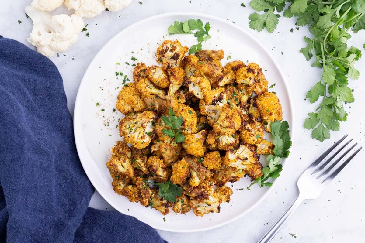 Curry-roasted cauliflower is served on a white plate.