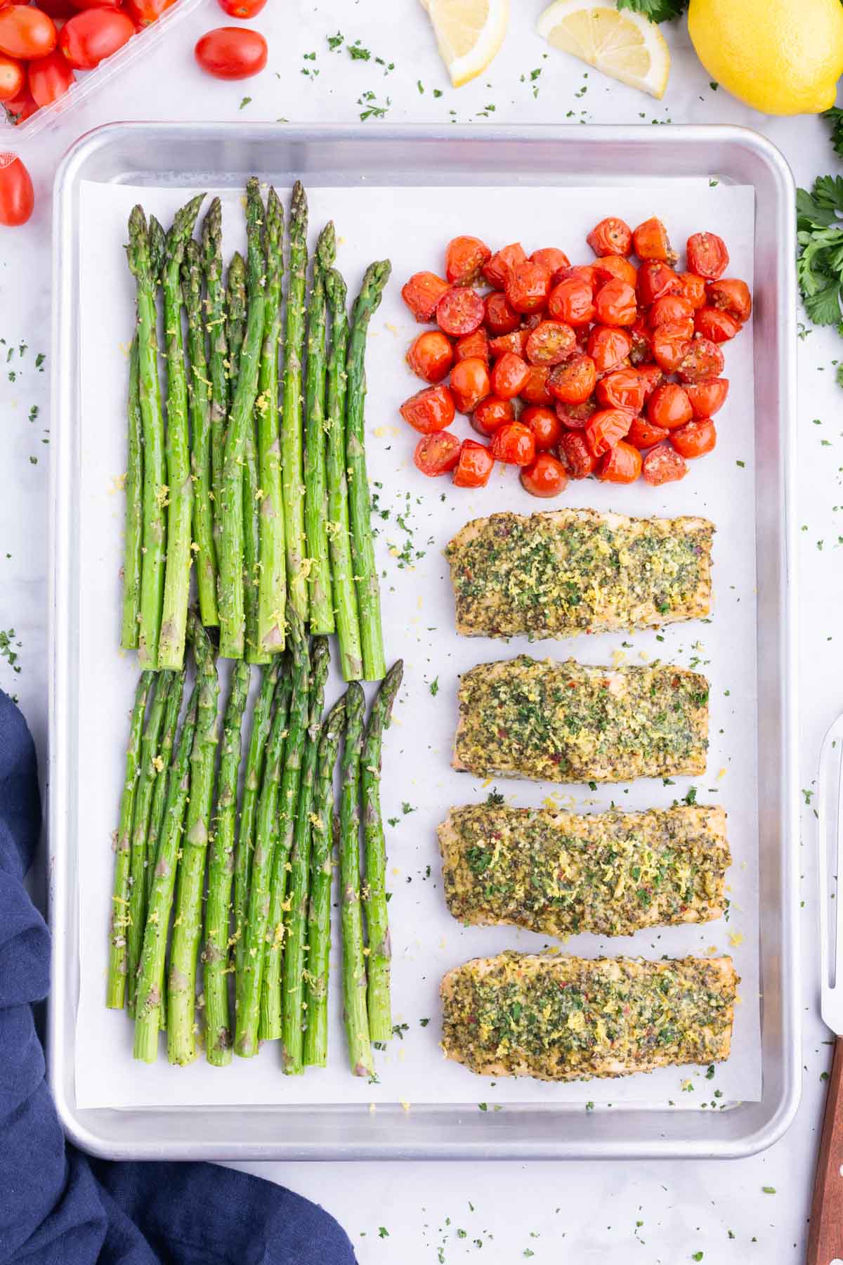 A sheet pan full of roasted asparagus, basil pesto salmon and roasted cherry tomatoes.