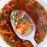 A spoon scoops out some Vietnamese fish sauce from a bowl.