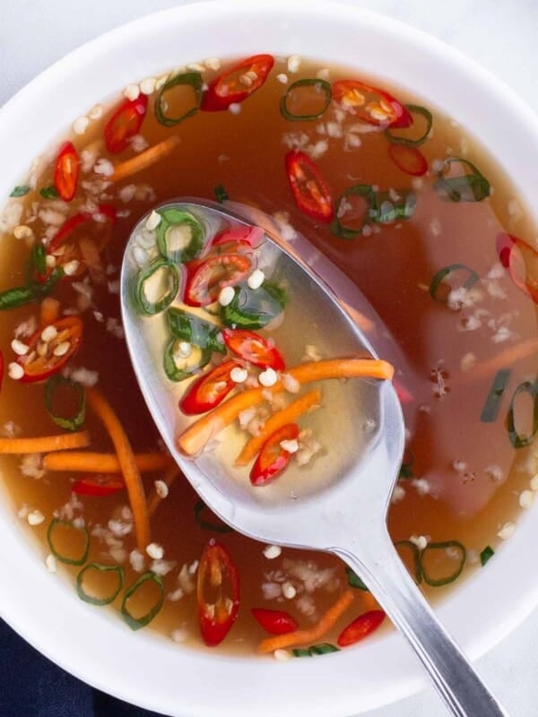 A spoon scoops out some Vietnamese fish sauce from a bowl.