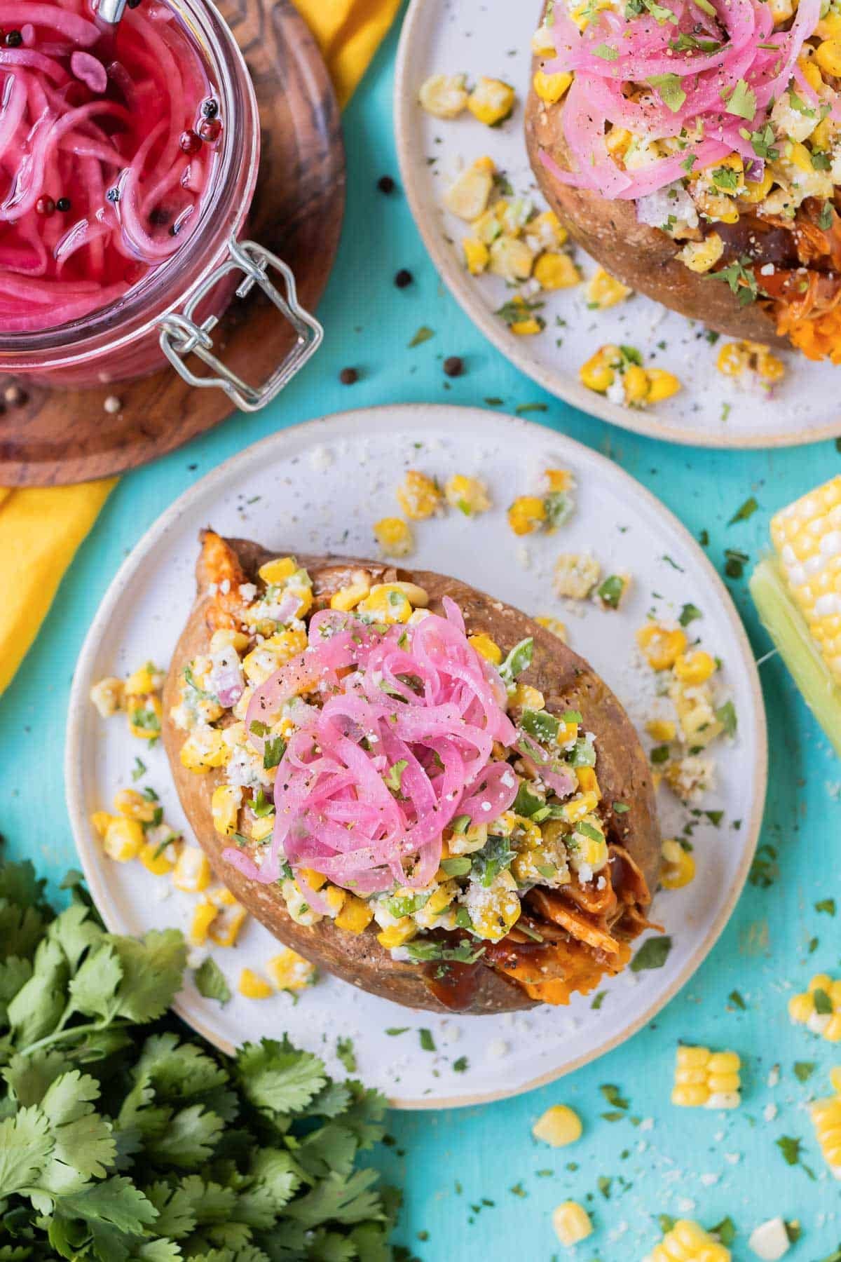 BBQ chicken stuffed sweet potatoes on a sheet pan, topped with Mexican street corn salad.