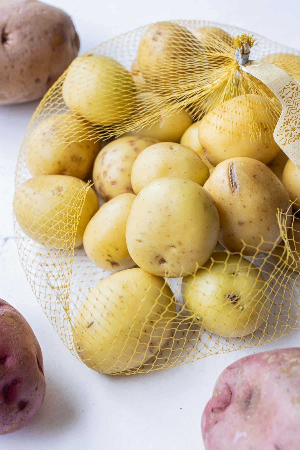 A bag full of yukon gold potatoes, red potatoes, and russet potatoes that will be used in a how to boil potatoes recipe.