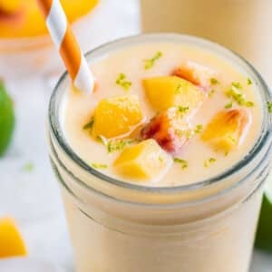 A frozen peach banana smoothie is served in a glass with a straw.
