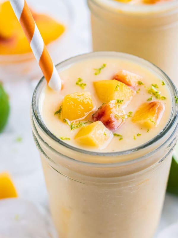 A frozen peach banana smoothie is served in a glass with a straw.