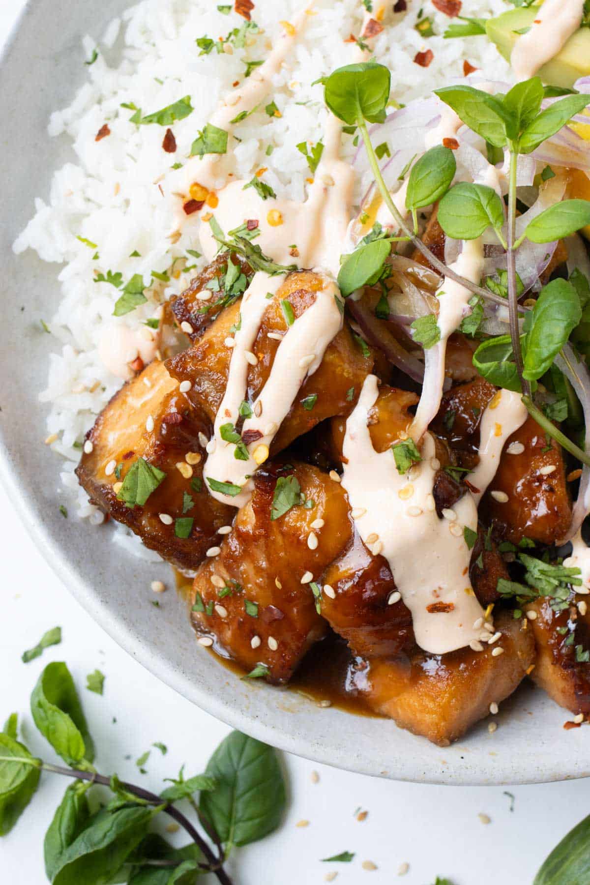 Teriyaki salmon bowls are filled with coconut milk, mangoes, and sriracha mayo.