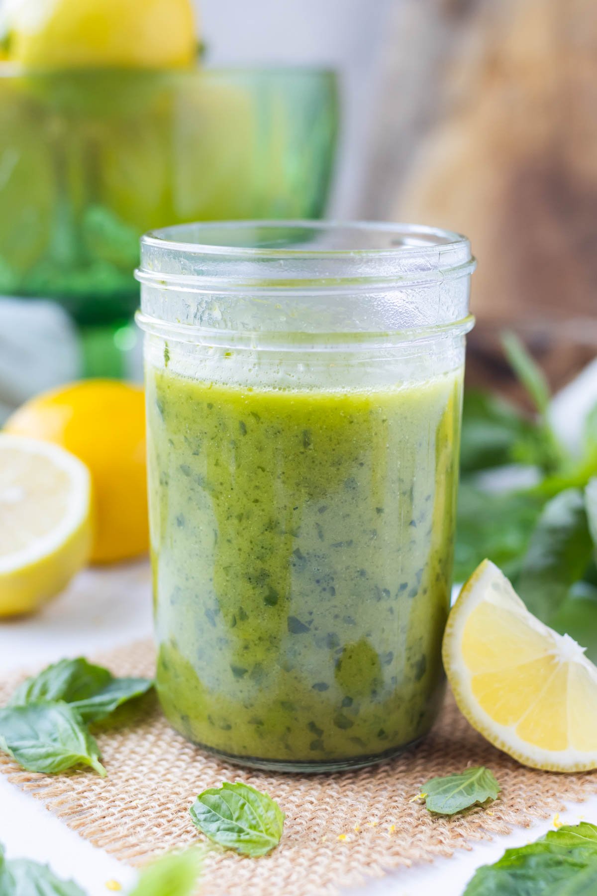 A mason jar is full of a lemon vinaigrette with basil.