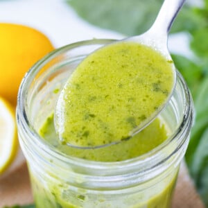 A metal spoon is used to serve lemon basil vinaigrette from a Mason jar.