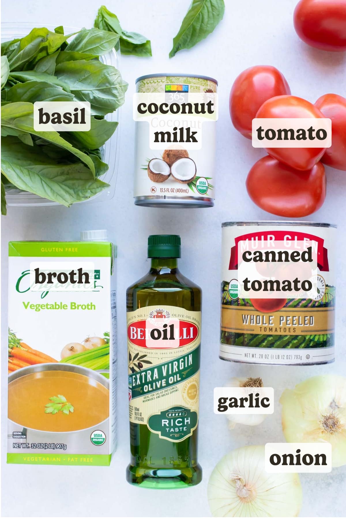Fresh and canned tomatoes, basil, broth, oil, onions, garlic, coconut milk as the ingredients for a vegan tomato soup recipe.