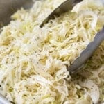 Tongs are used to stir and serve apple cider slaw.