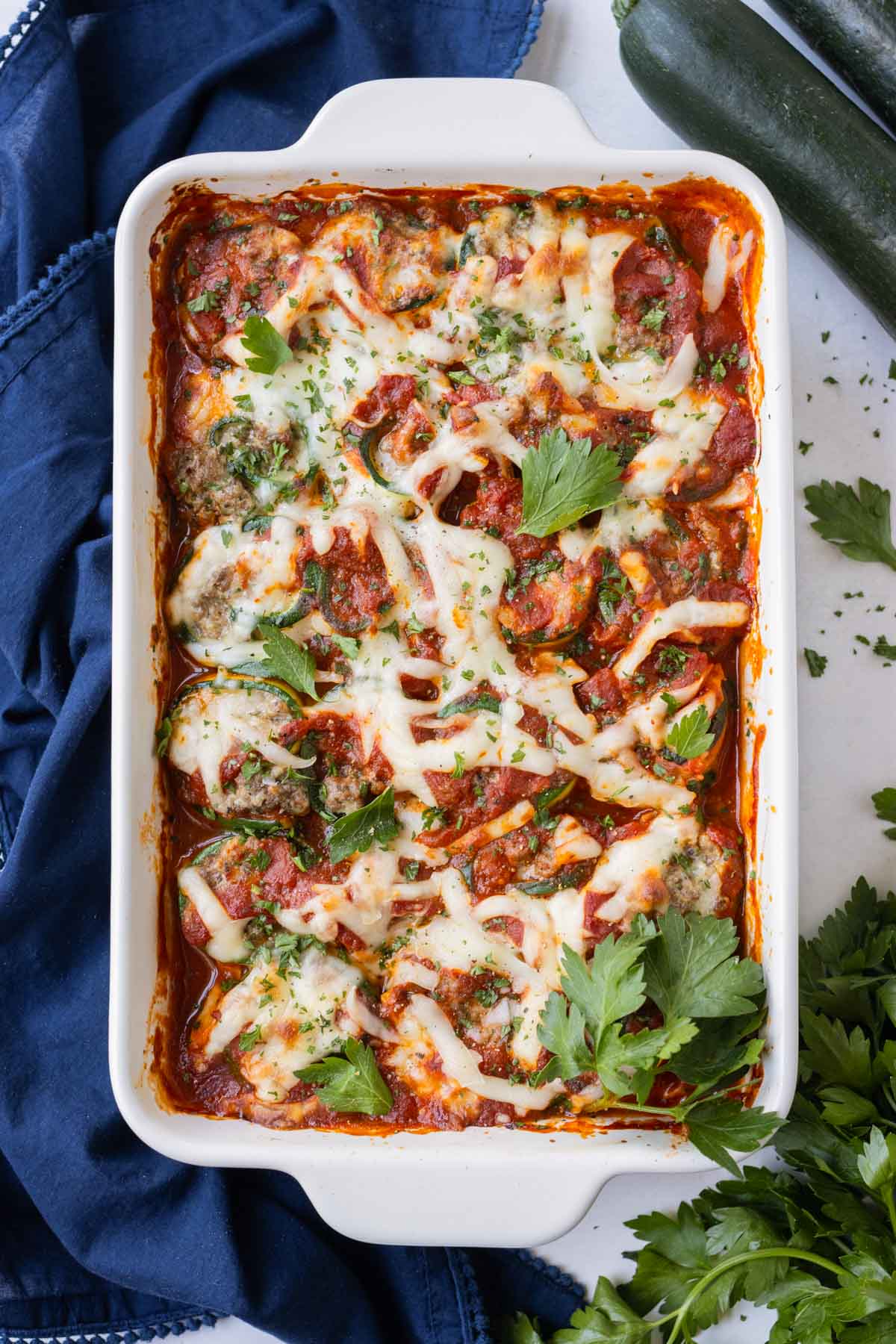 A baking dish full of zucchini lasagna roll-ups with marinara sauce.