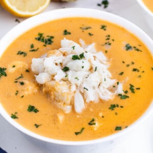 Creamy crab bisque is in a white bowl with jumbo lump crab meat on top.