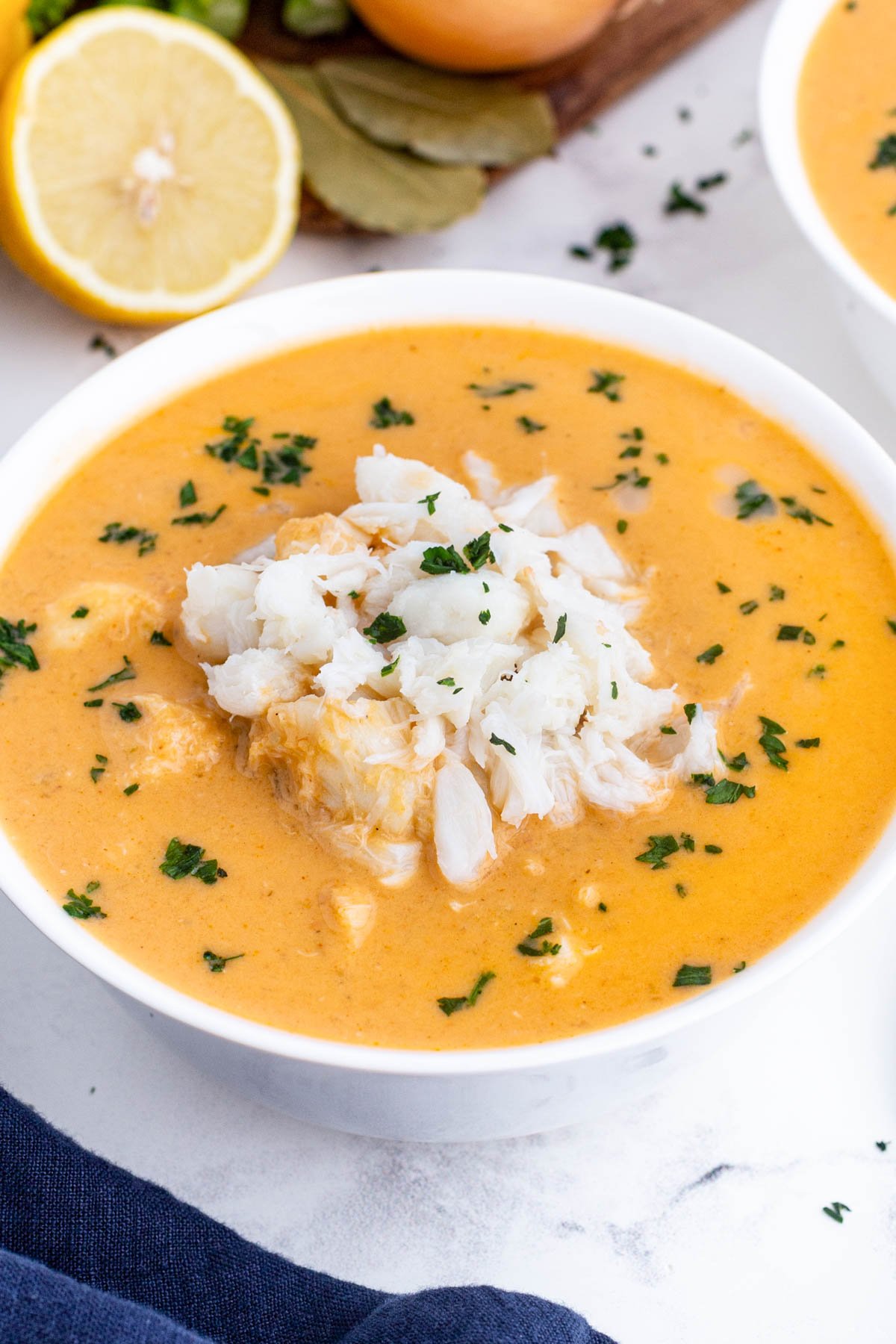 Creamy crab bisque is in a white bowl with jumbo lump crab meat on top.