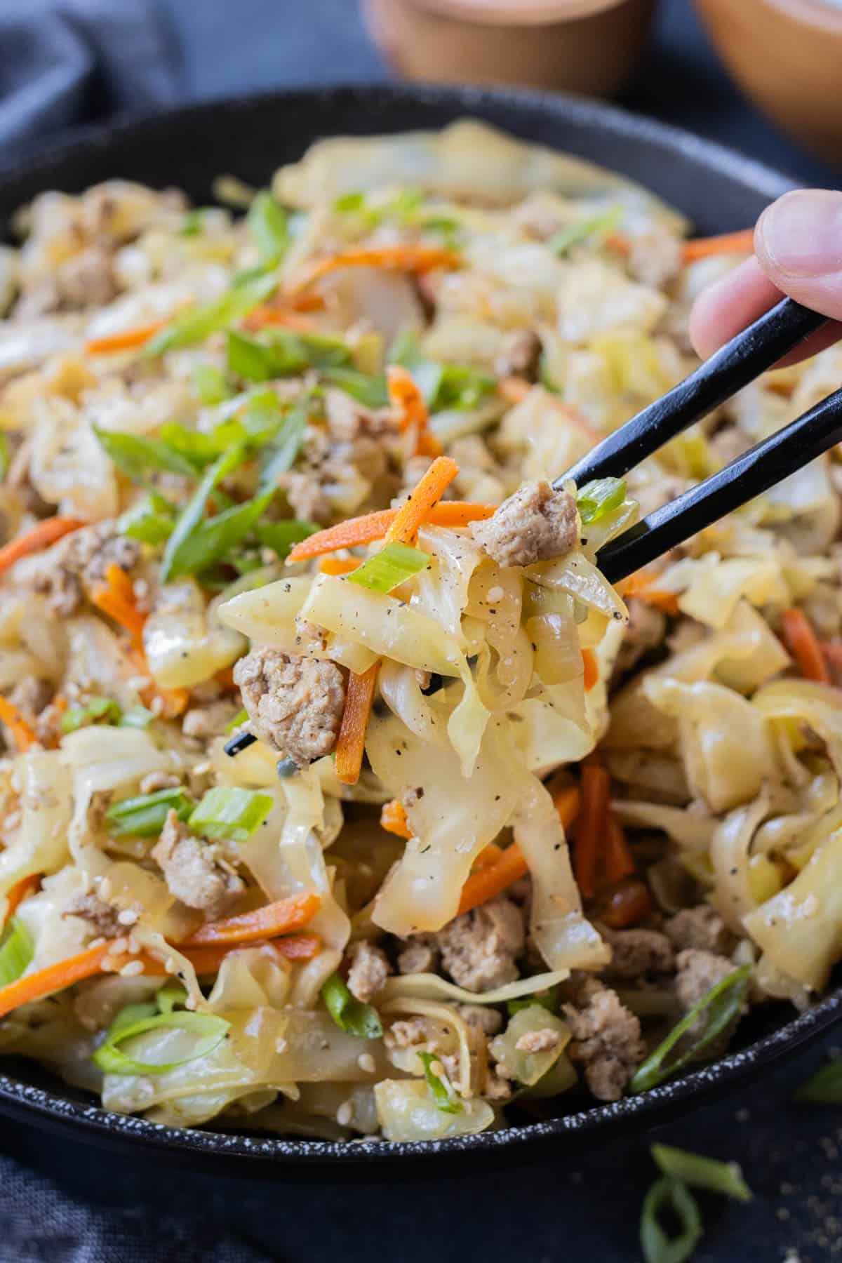 Chopsticks are used to dig into a serving of egg roll in a bowl.