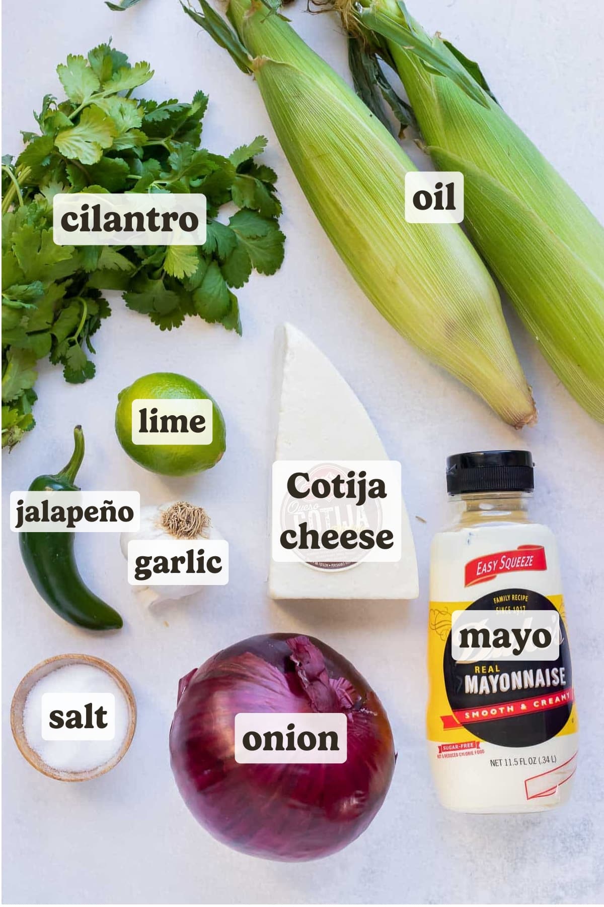 Fresh corn on the cob, cilantro, lime, jalapeno, mayonnaise, red onion, and cotija cheese as ingredients for a street corn salad.