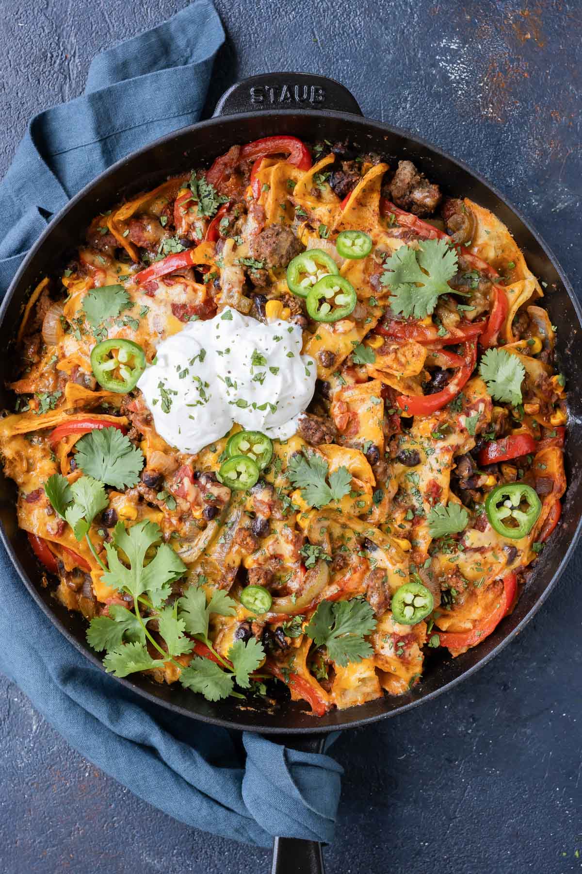 A ground beef taco skillet is topped with jalapenos, cilantro, and sour cream.