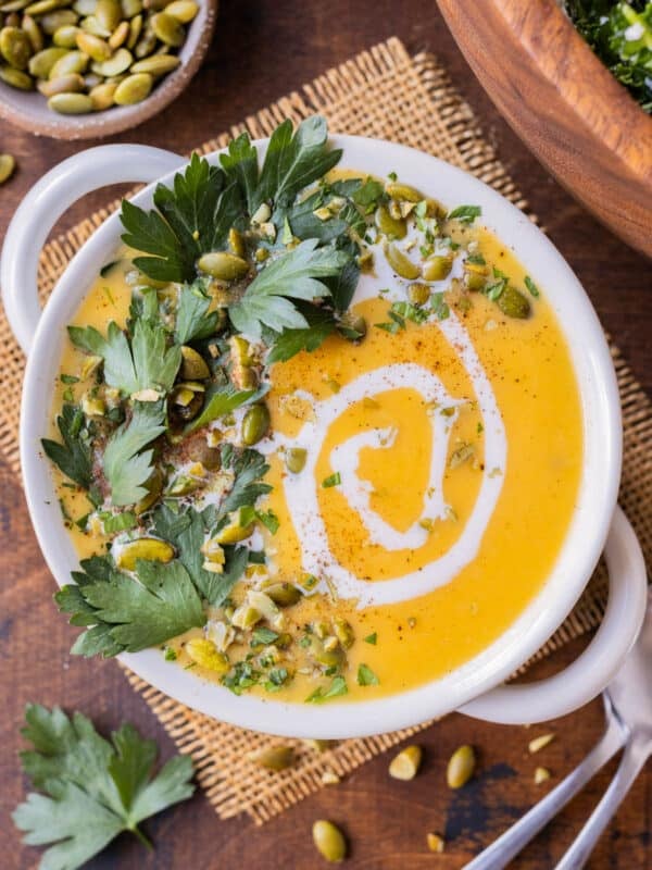 Roasted Butternut Squash Soup is served in a white bowl with a drizzle of coconut milk on top.