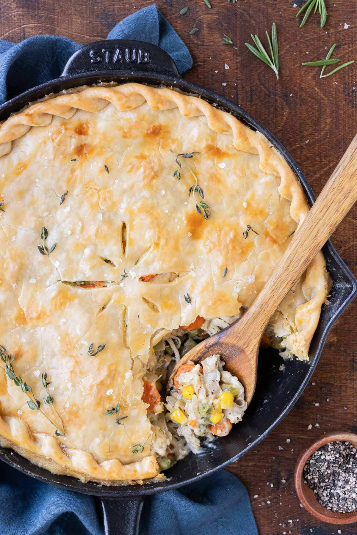A wooden spoon is used to scoop a serving of skillet chicken pot pie.