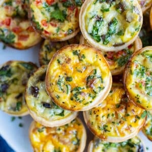 A variety of mini quiches are served on a party tray as a holiday appetizer.
