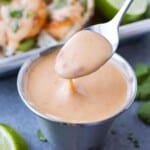 A small glass bowl is full of Bang Bang sauce and served with tacos.