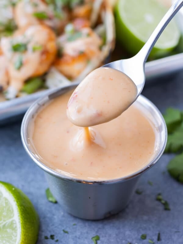 A small glass bowl is full of Bang Bang sauce and served with tacos.