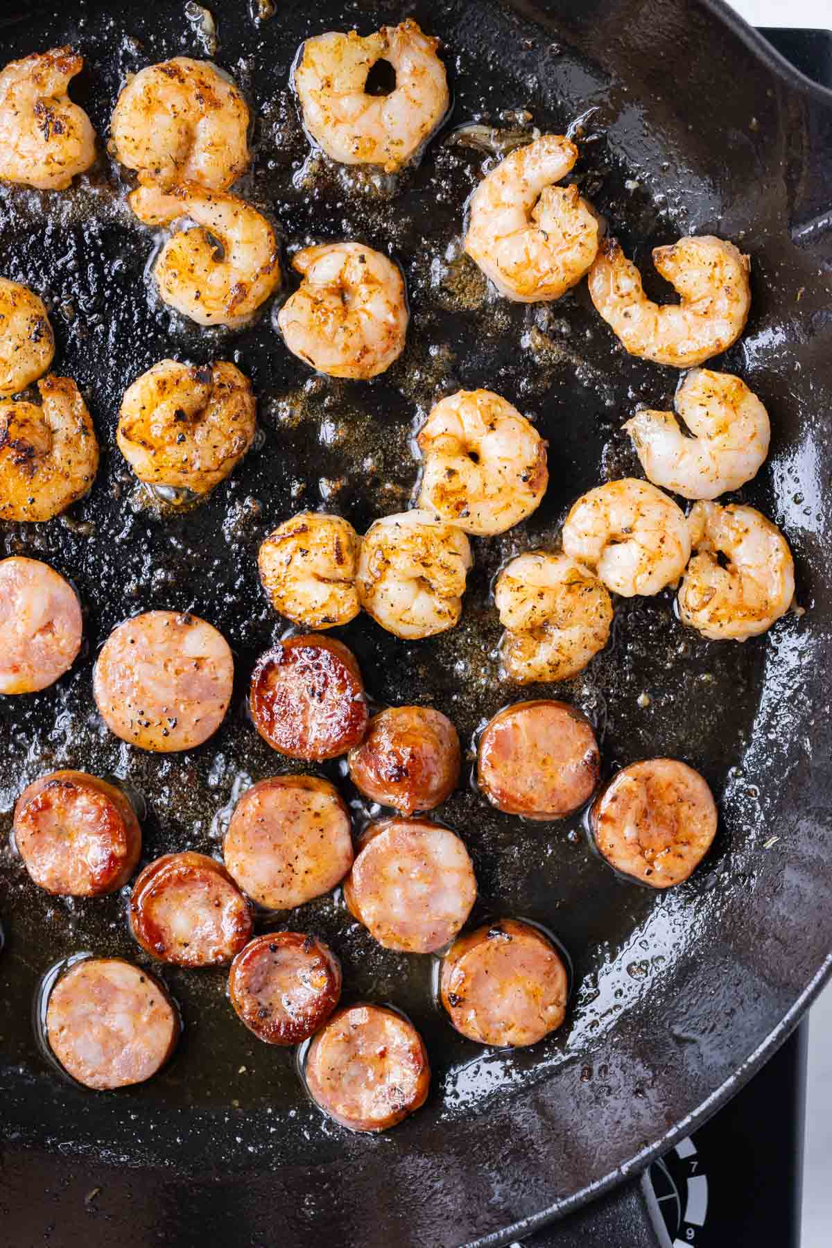 Seasoned shrimp and sausage are cooked in a cast iron skillet.