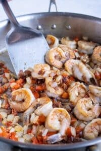 Large gulf shrimp are seared with Cajun blackened seasoning in a skillet.