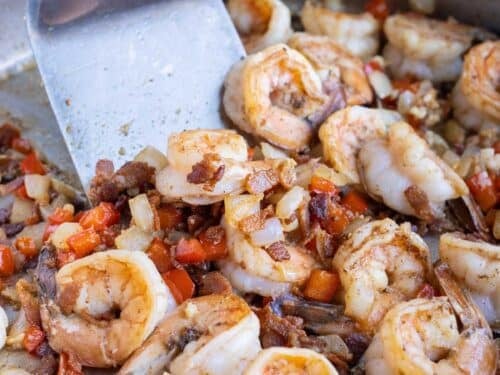 Large gulf shrimp are seared with Cajun blackened seasoning in a skillet.