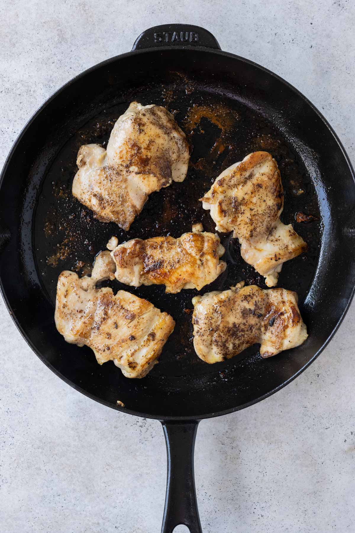 Greek seasoned chicken is cooked in a skillet.