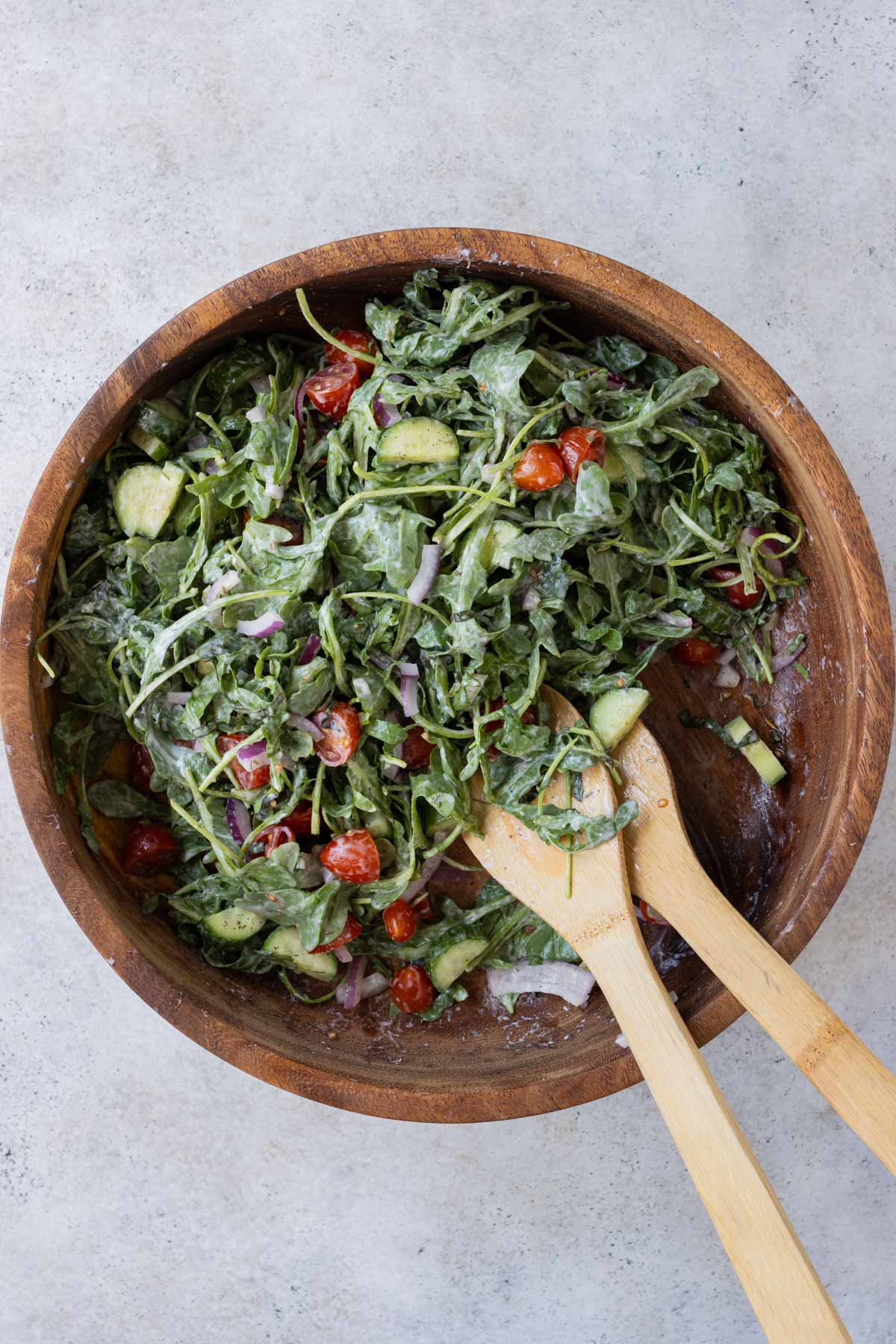 The arugula salad is tossed together in a bowl.