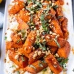 Spiced roasted carrots are served on a plate with a lemon Greek yogurt sauce and a drizzle of hot honey.