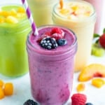Five different frozen fruit smoothies are set on a counter.