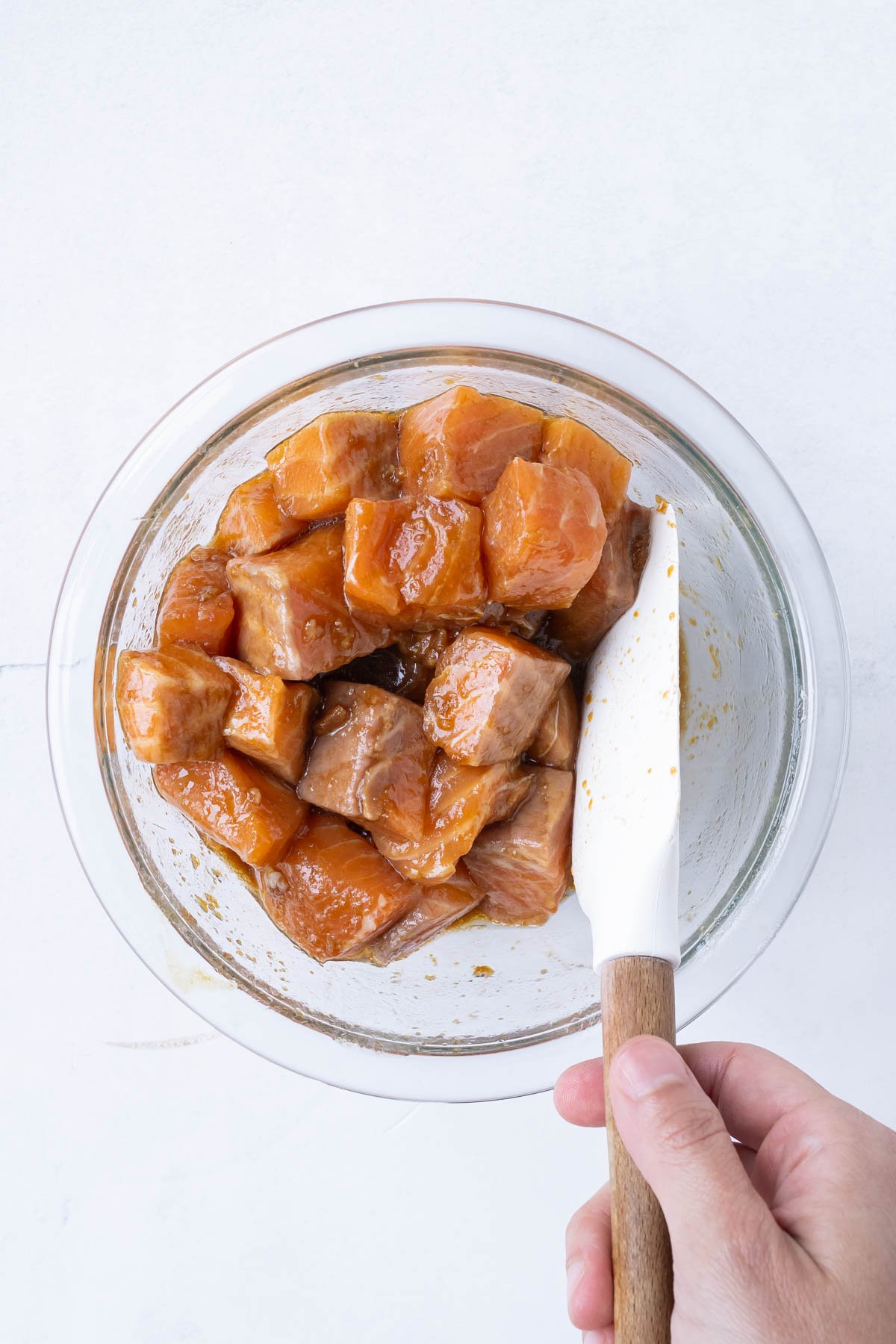 Salmon cubes are stirred into a sauce.
