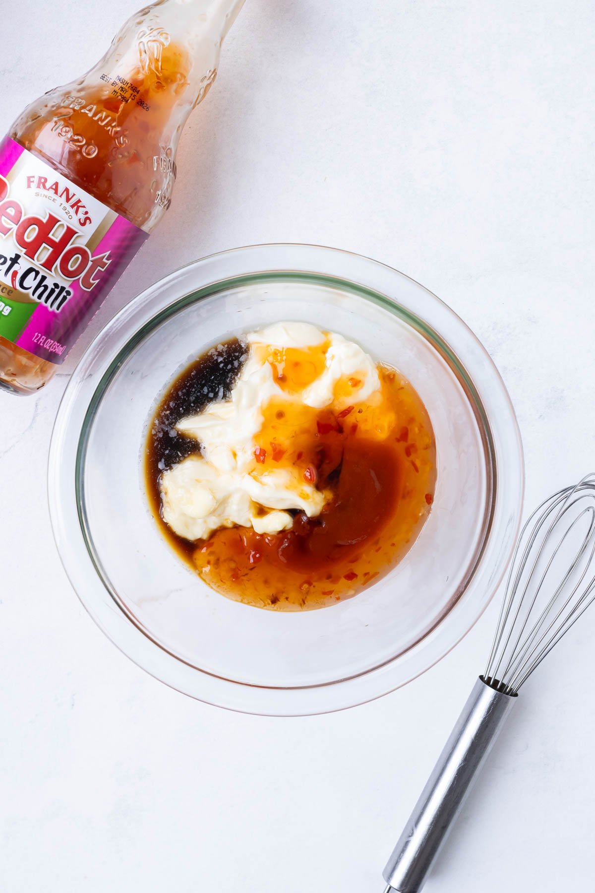 Bang bang sauce is stirred together in a glass bowl.
