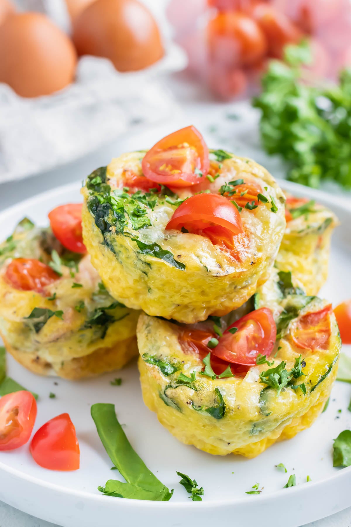A close-up of a spinach egg muffin with tomato and melted mozzarella.