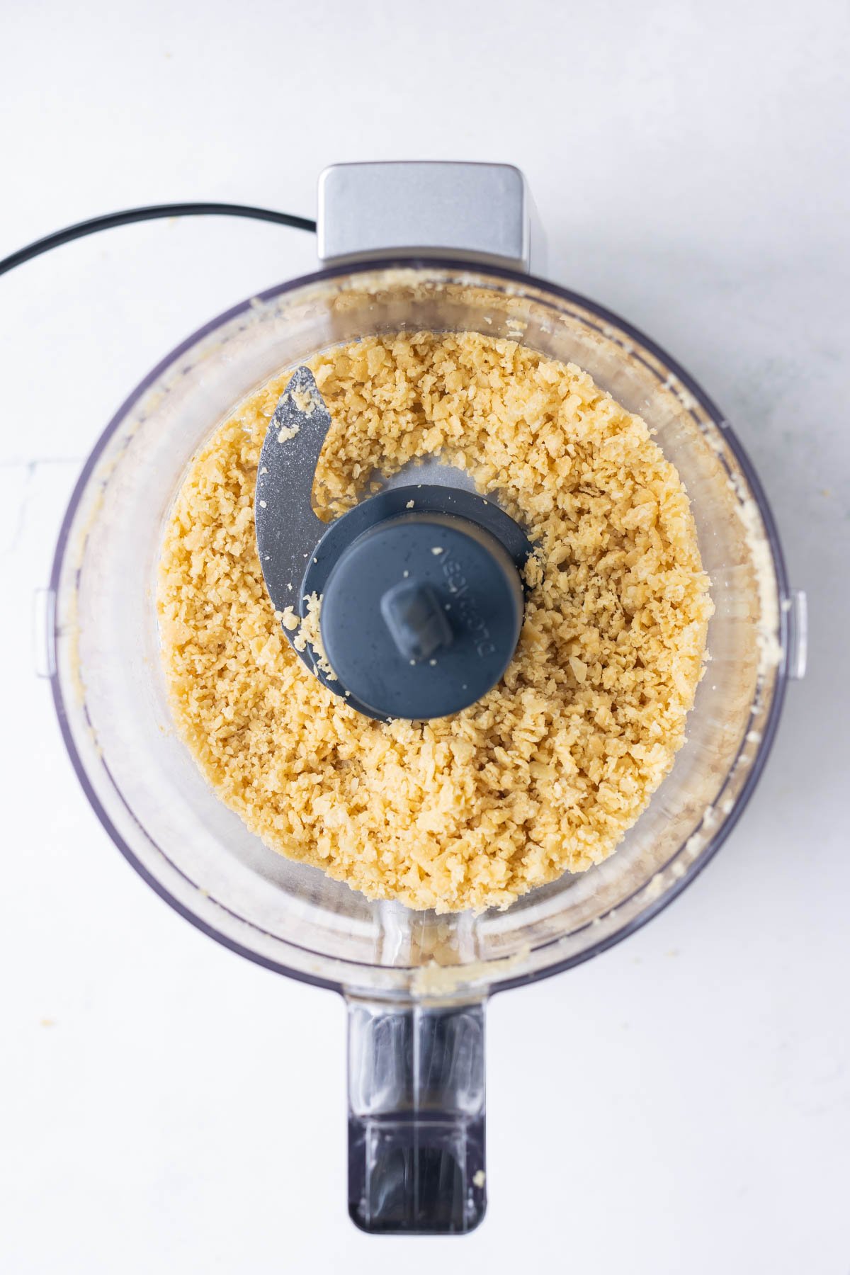 Tortilla chips are ground up in a food processor.