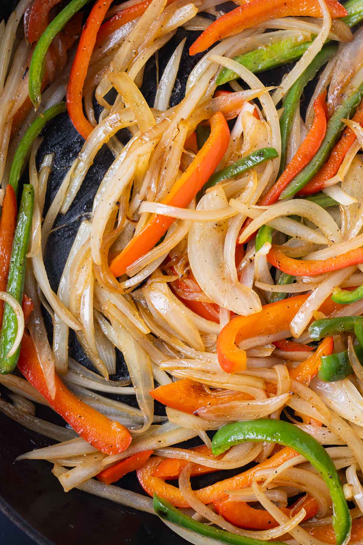 Onions and peppers are sauteed in a skillet.