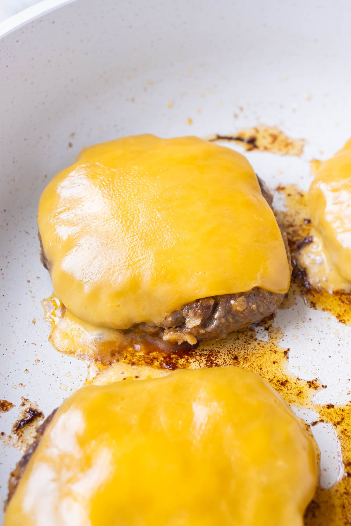 Cheese is added to the cooked patties.