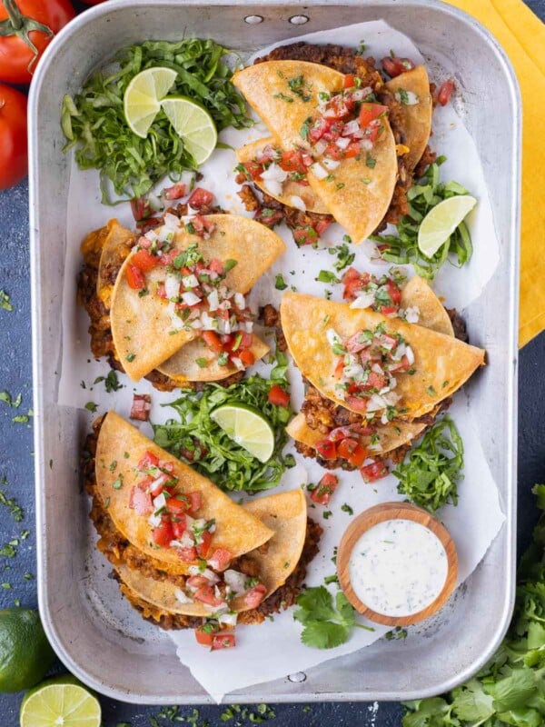 A tray full of crispy baked tacos with ground turkey, cheese, and beans is served with a cilantro lime ranch.