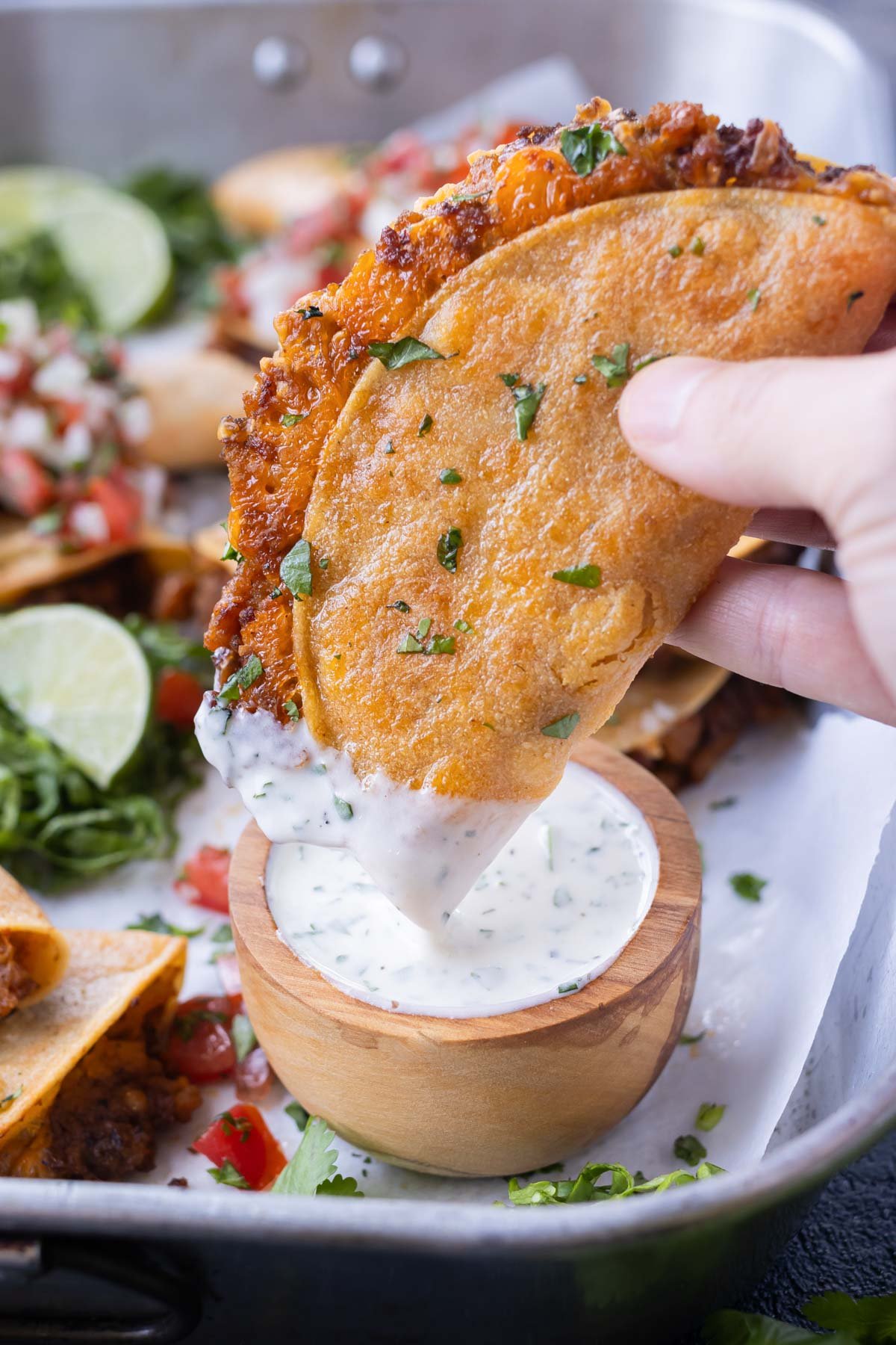A hand dips a baked turkey taco into a ranch dressing.