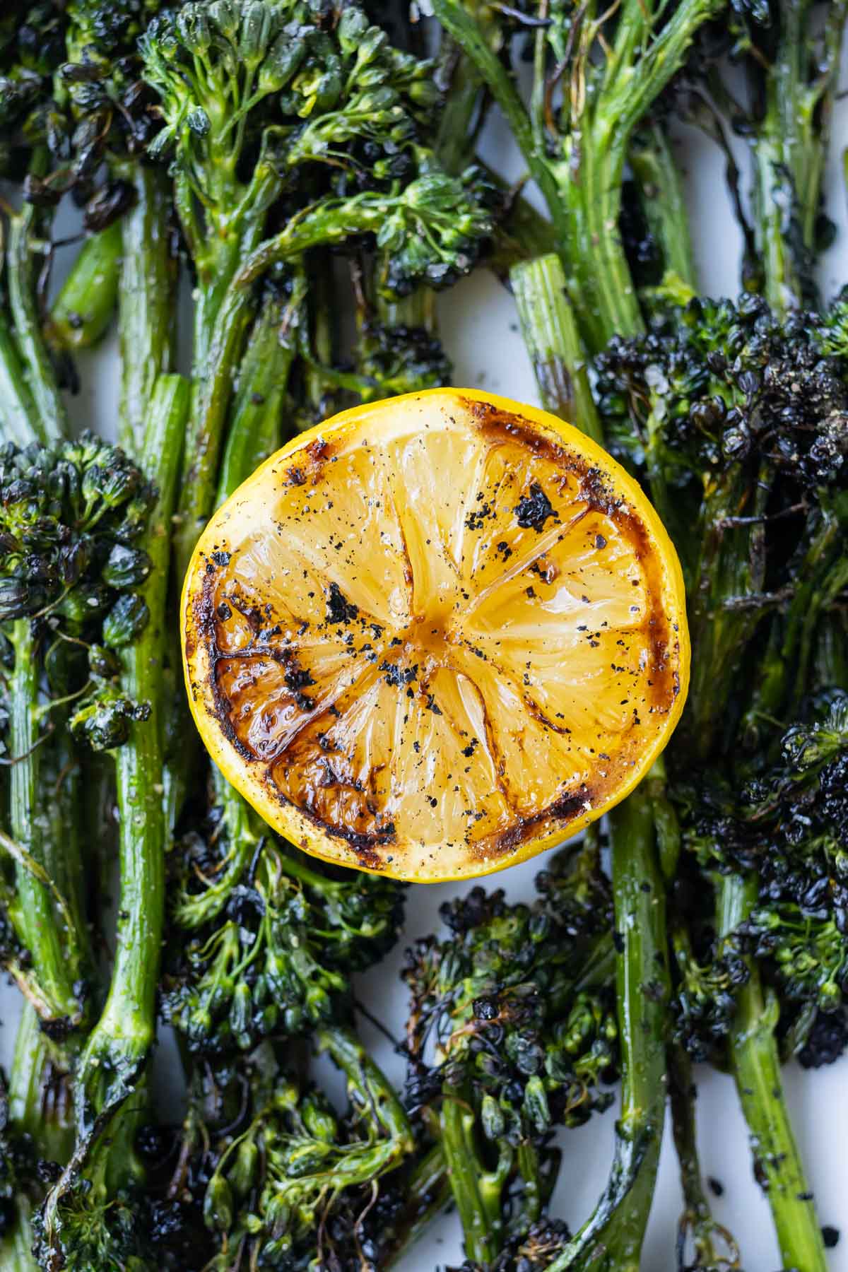 Charred lemon is served with grilled broccolini for a zesty bite.