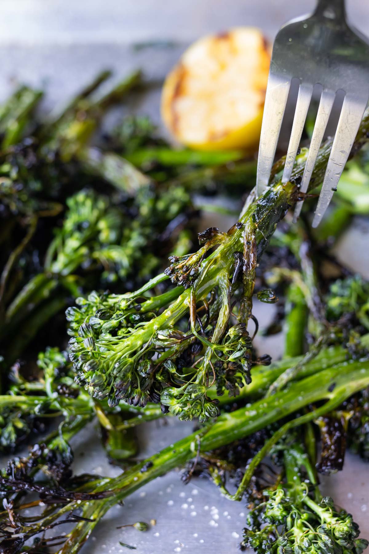 A fork picks up a broccolini stalk from the grill.