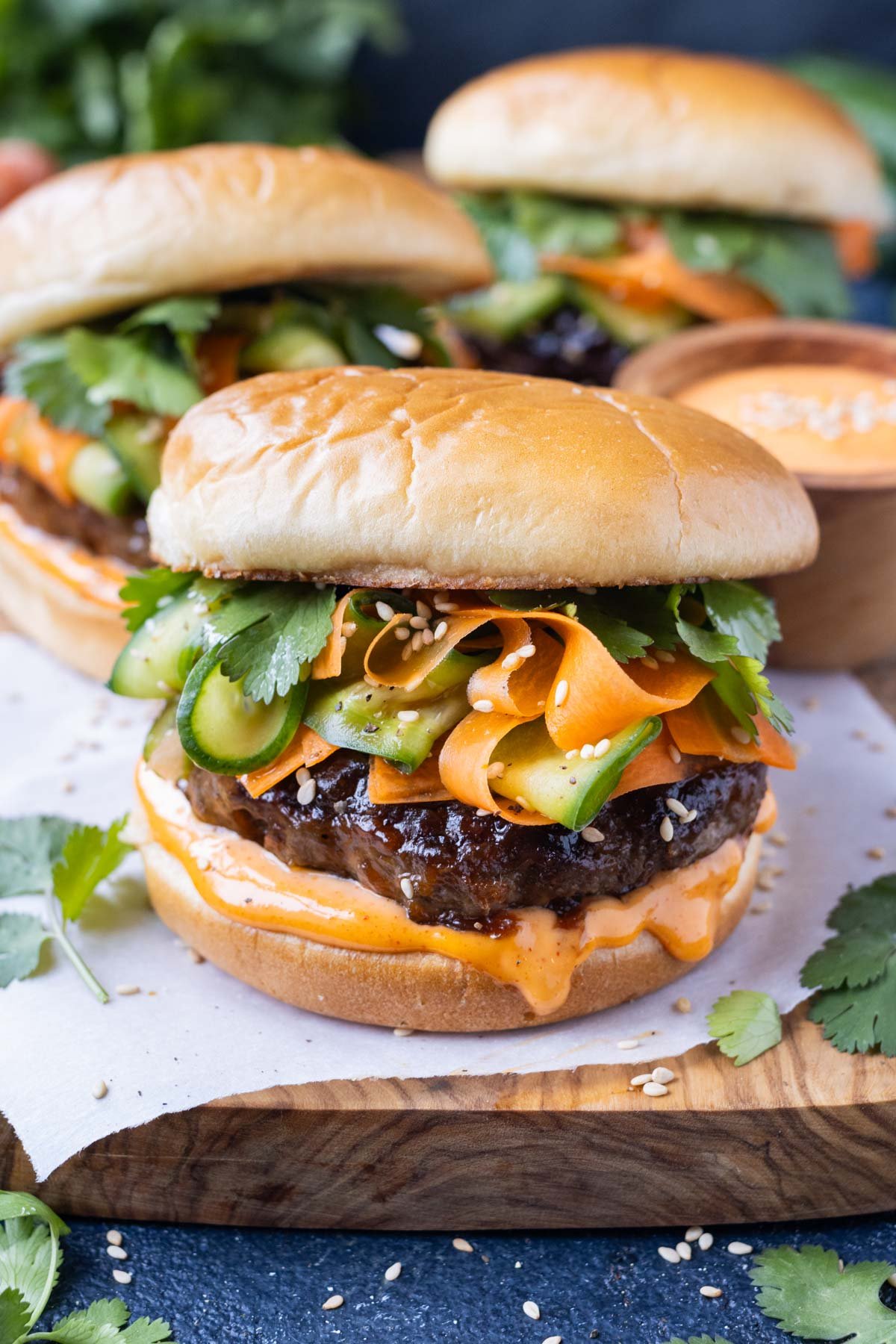 Korean beef burgers are topped with a carrot and cucumber slaw and gochujang mayo and served on a plate for dinner.