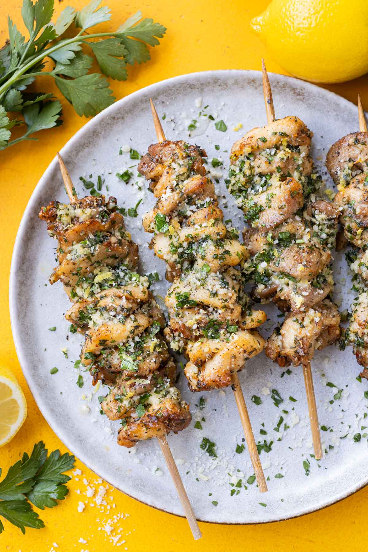 Air fryer garlic Parmesan chicken skewers are served on a plate with parsley.