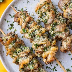 Air Fryer Garlic Parmesan Chicken Skewers are served on a white plate with parsley sprinkled on top.
