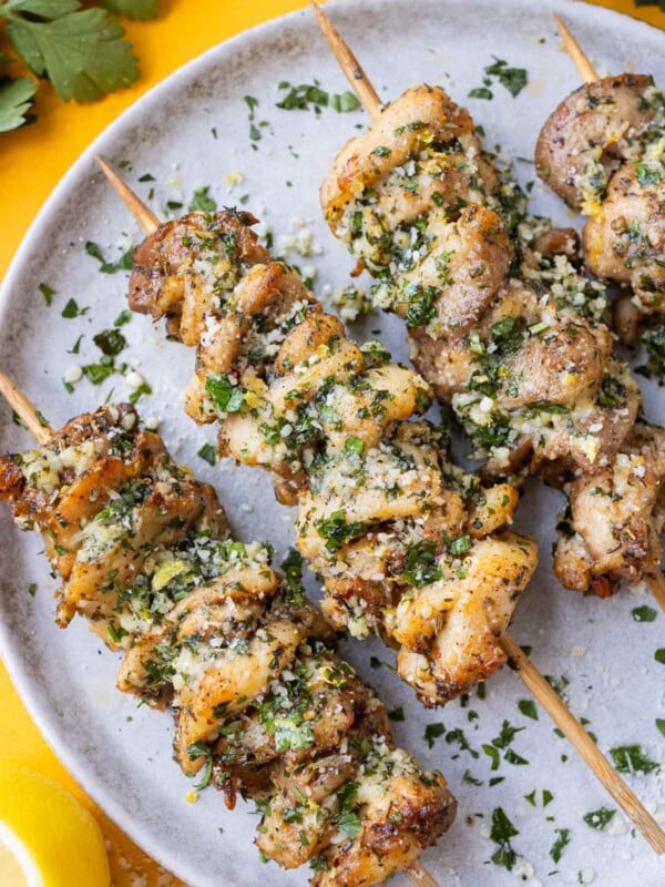 Air Fryer Garlic Parmesan Chicken Skewers are served on a white plate with parsley sprinkled on top.