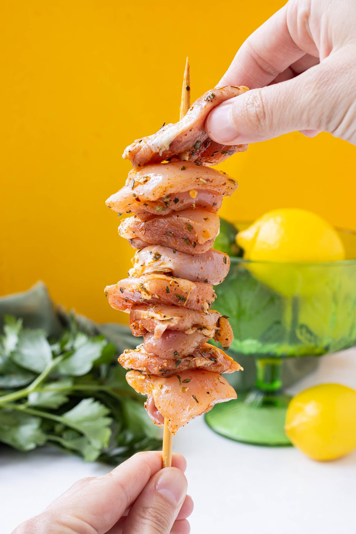 Seasoned pieces of chicken thighs are added a skewer.