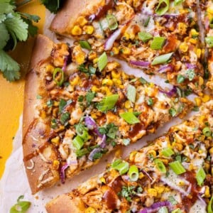 BBQ Chicken Pizza with summer corn, red onions, and barbecue sauce has been cut into slices for serving.