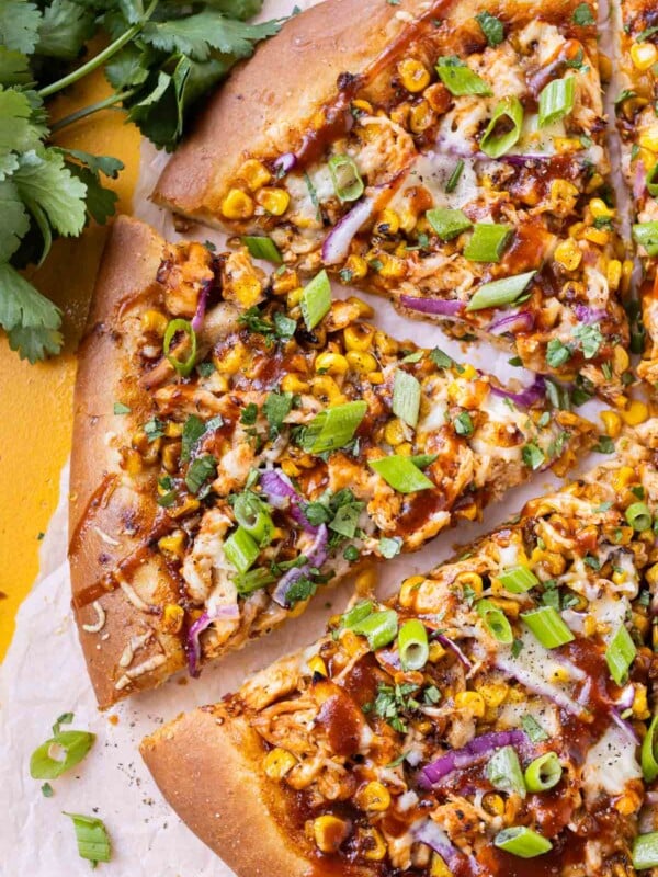 BBQ Chicken Pizza with summer corn, red onions, and barbecue sauce has been cut into slices for serving.