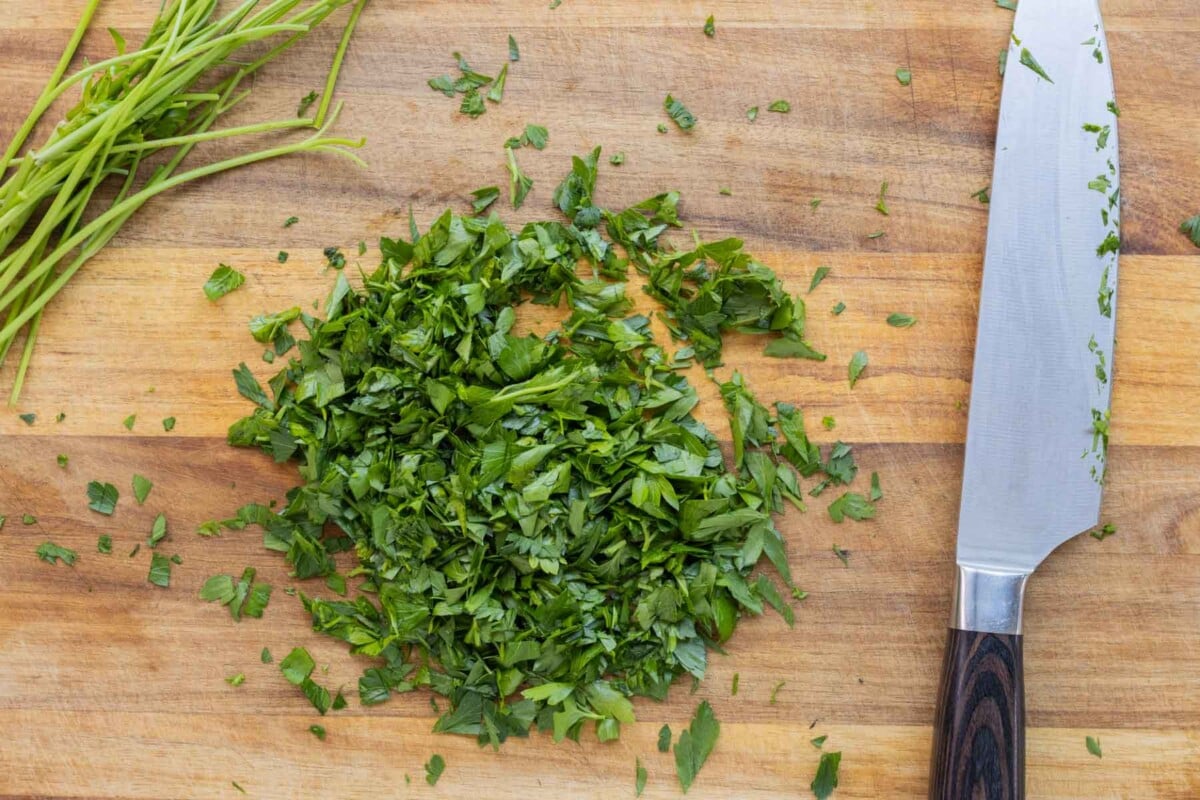 Parsley is chopped on a cutting board.