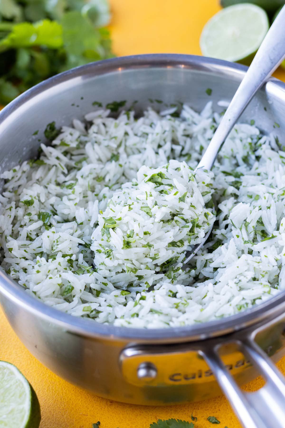 A spoon stirs a pot of coconut milk cilantro lime rice.